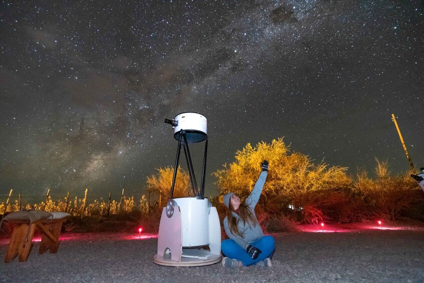 A person observing the night sky through a telescope, with a starry sky and autumn trees in the background. 1