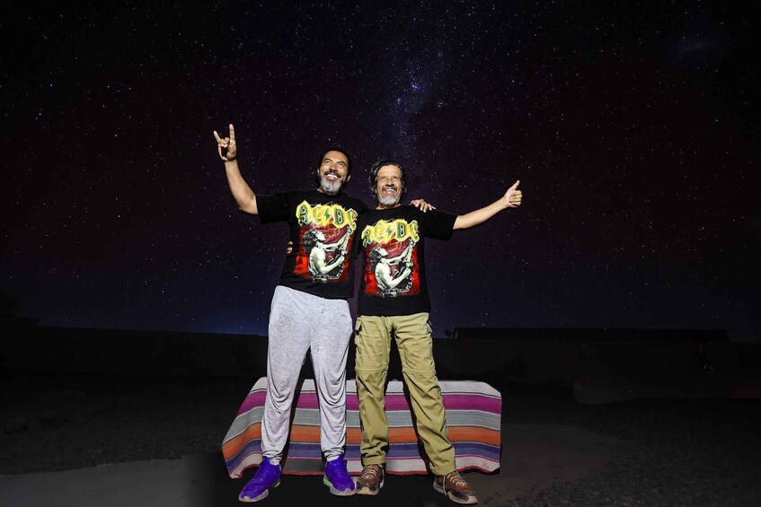 Two people standing on a striped platform with a starry night sky in the background. 3
