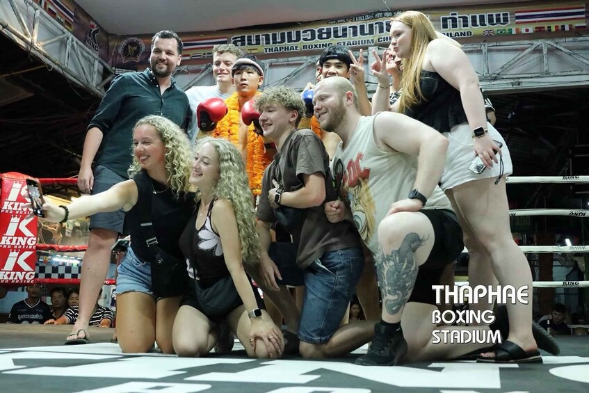 A group of people in a boxing ring with a banner reading 'THAPHAE BOXING STADIUM'. 4
