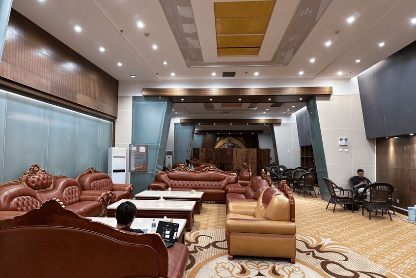 A spacious lounge with leather sofas, a patterned carpet, and a ceiling with recessed lighting. 2