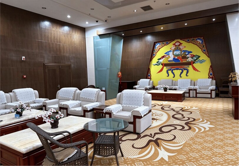 A traditional room with sofas, a glass table, and a decorative wall painting. 1