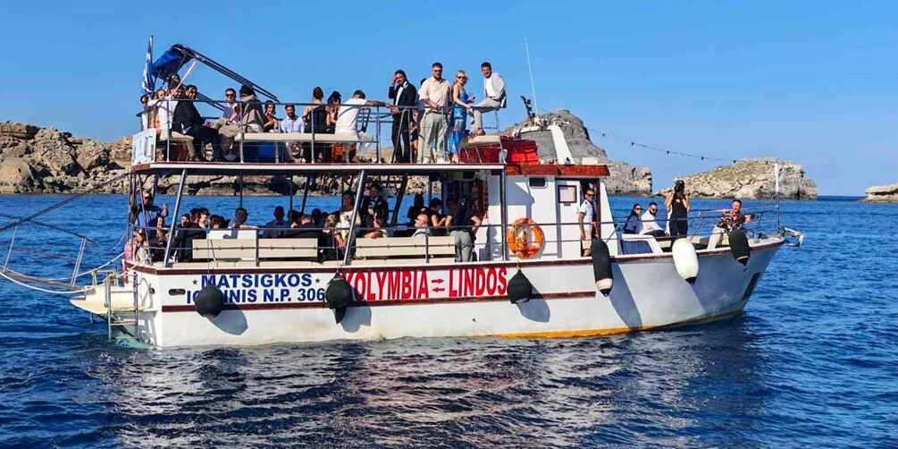 A boat named 'MATSIGKOS' with passengers on board, sailing near rocky coastlines. 4