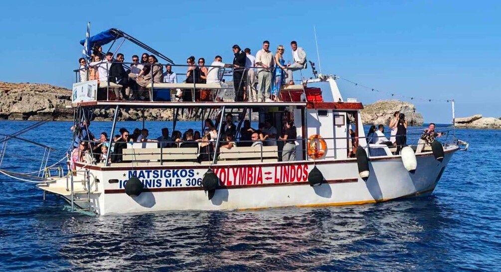 A boat with people on board, named 'MATSIGKOS,' sailing on the water. 2