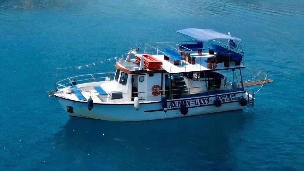 A white boat with a blue canopy and a red lifebuoy on calm blue water. 2