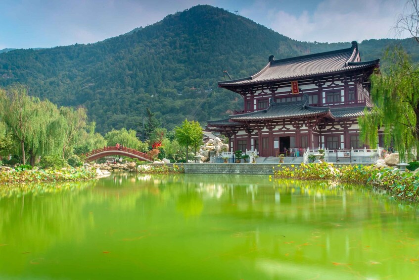 A traditional Japanese temple with a pond in the foreground and a mountain in the background. 5