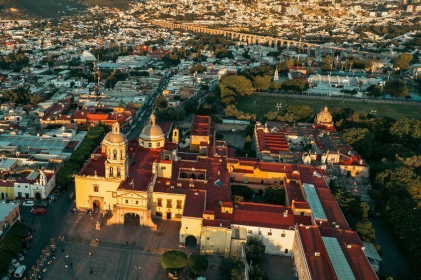 An aerial view of a city with a prominent church, a bridge, and surrounding buildings. 1