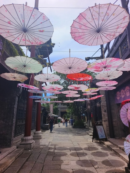 A street with hanging umbrellas and traditional architecture. 2