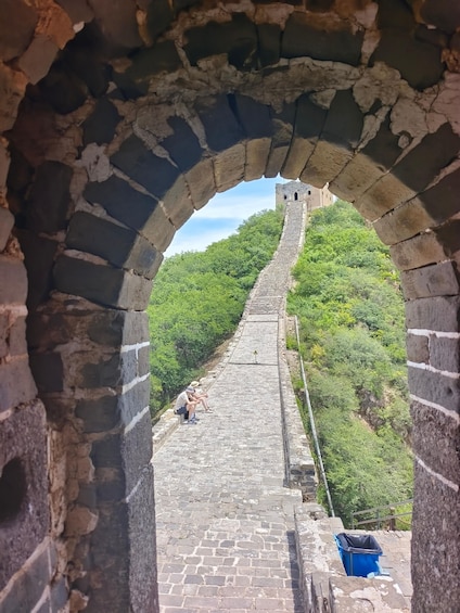 An ancient stone wall with a view of a lush green hillside. 3