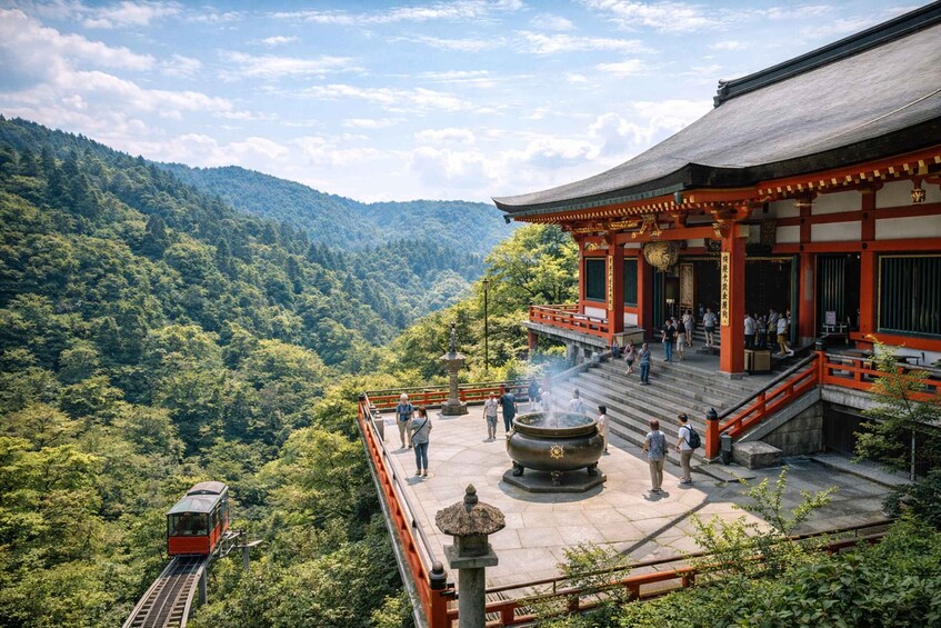 A traditional Japanese temple with a train on a track above a forested valley. 4