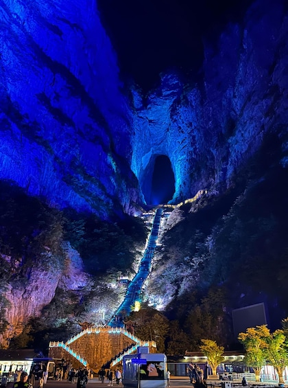 A nighttime view of a cave with a blue-lit tunnel and a stone staircase leading into it. 3