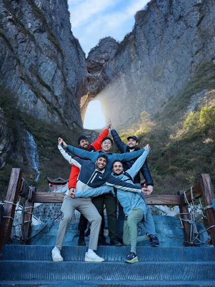 A group of people on stone steps with a natural rock arch in the background. 4