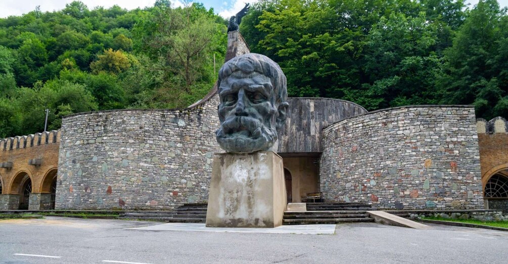 A stone building with a large statue in front. 3