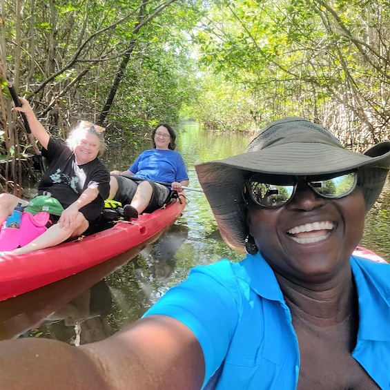 Two people in a red kayak on a calm river surrounded by dense mangrove trees. 5