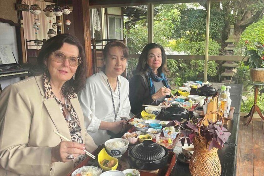 Three people dining at a table with various dishes and a traditional tea set. 5