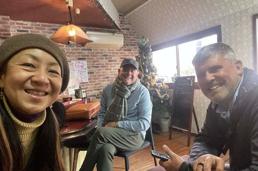 Three people sitting at a table in a cafe with a brick wall and a Christmas tree in the background. 3