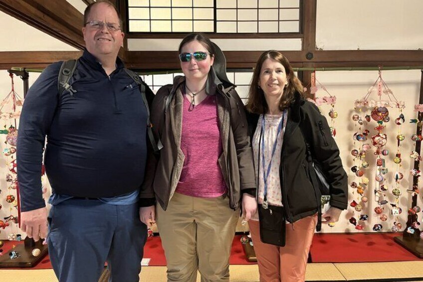 Three people standing in a room with traditional Japanese decor. 3