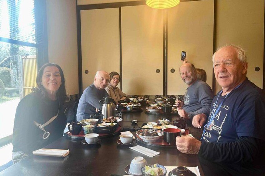 A group of people seated around a table with various dishes and drinks. 2
