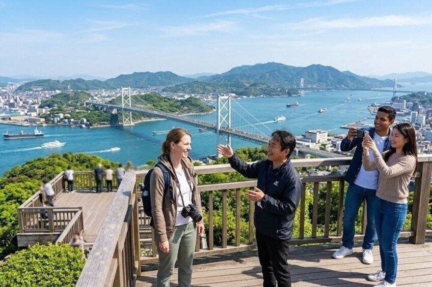 A group of people on a wooden deck overlooking a city with a prominent bridge and waterway. 1