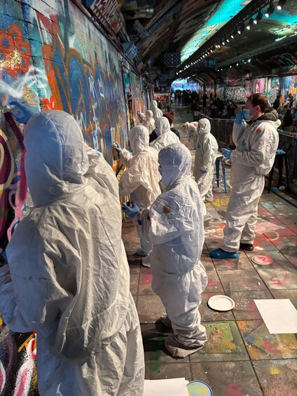 People in protective gear painting a colorful mural on a wall. 2