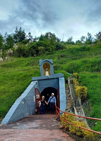 A tunnel entrance with a bell tower, surrounded by greenery and a brick pathway. 5