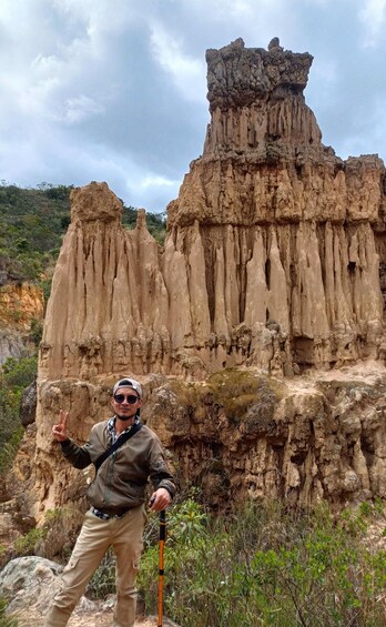 A person standing in front of a rock formation with vertical striations and a flat-topped peak. 4