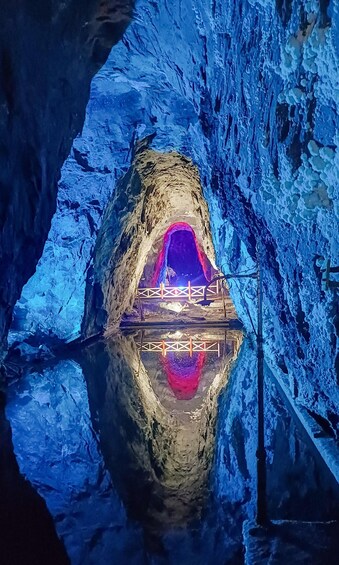 A cave with a reflective water surface and a wooden walkway leading to a cave opening. 2