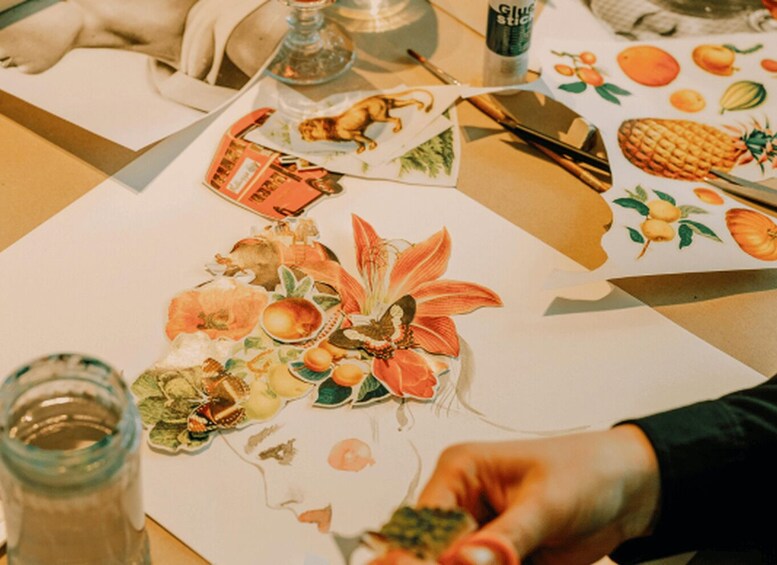 A person working on a collage with various paper cutouts and a glue stick on a table. 2