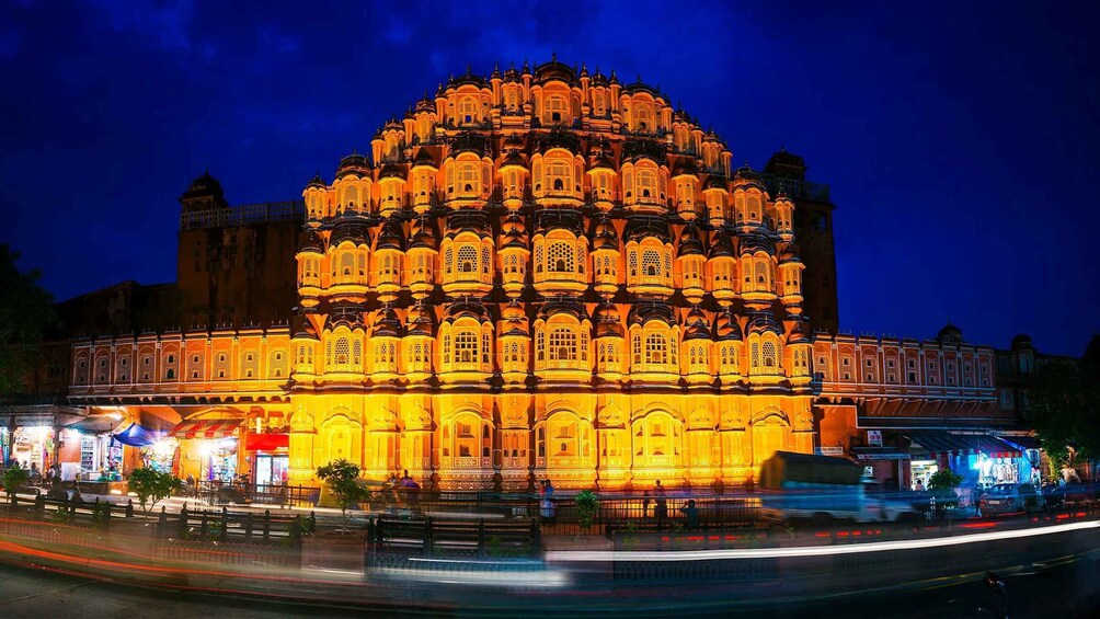 A brightly lit, ornate building with multiple domes and arches, surrounded by a busy street with light trails from moving vehicles. 4