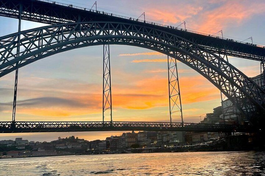 A large steel bridge arching over a river with a sunset in the background. 2