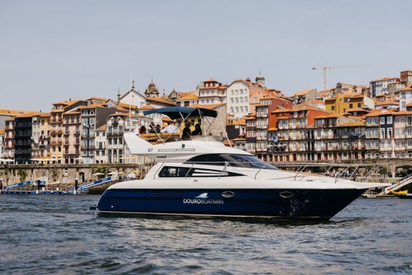 A yacht named 'Douro' docked at a harbor with a backdrop of colorful buildings. 1