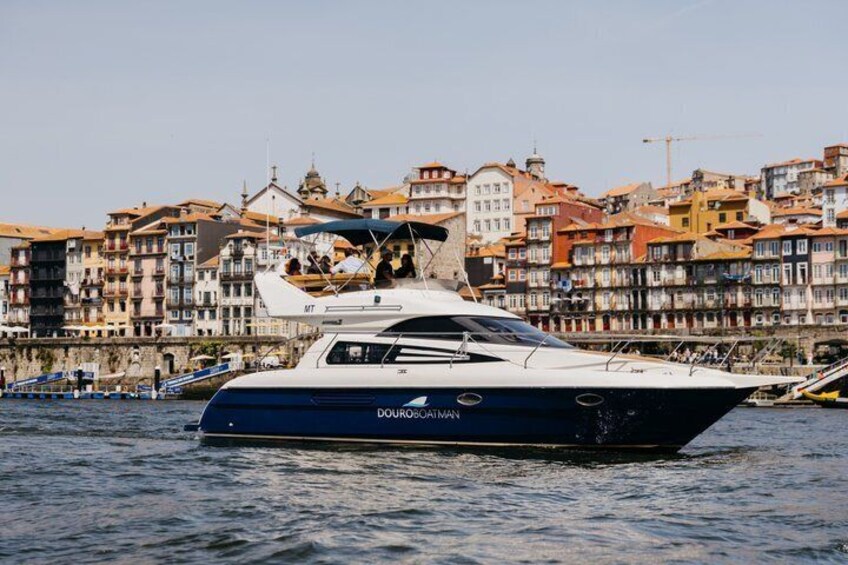 A yacht named 'Douro' on the water with a cityscape in the background. 1