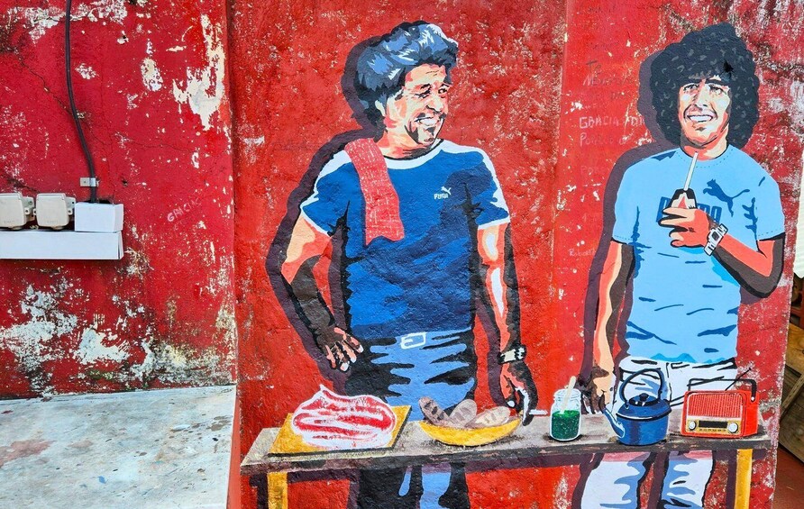 A mural of two men on a table with food and drinks. 1