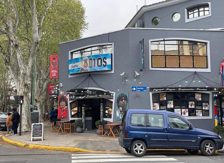 A street scene with a building featuring a large sign for 'Dios' and a pizza shop. 2