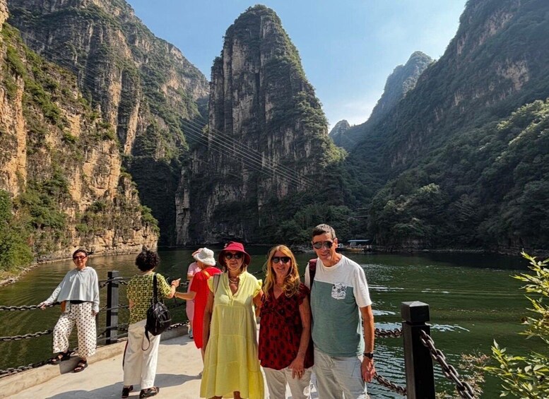A group of people standing on a bridge with a canyon and river in the background. 5