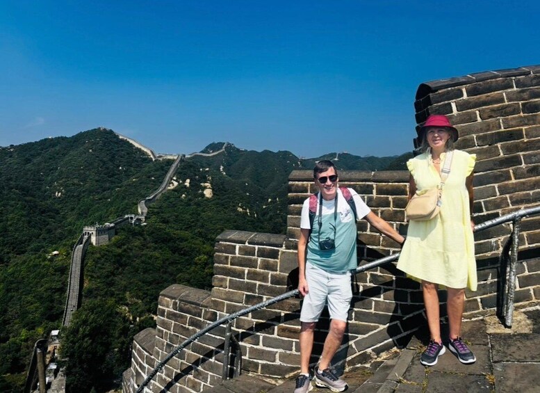 A man and a woman standing on the Great Wall of China, overlooking the surrounding landscape. 2