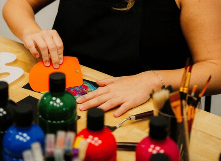 A person painting a wooden surface with various paint bottles and brushes. 2