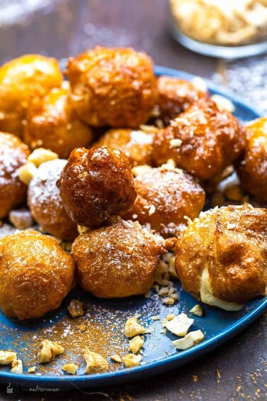 Une assiette remplie de petits gâteaux ronds, dorés et saupoudrés de sucre glace et de noix. 5