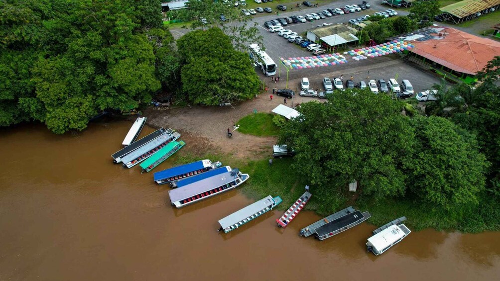 A river with boats docked on the bank, surrounded by dense greenery. 2
