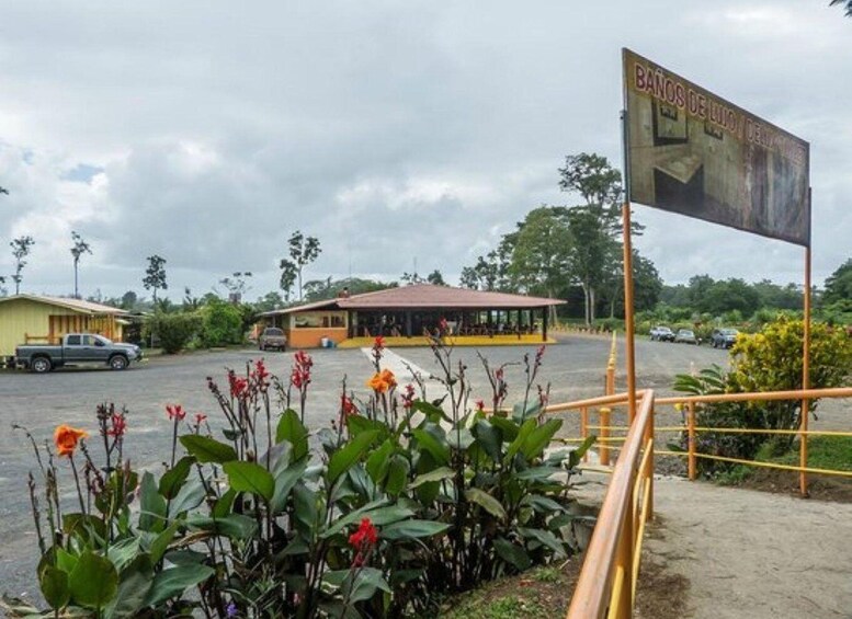 A building with a sign reading 'BAÑOS DE LAGO,' a parking lot, and a yellow truck. 1