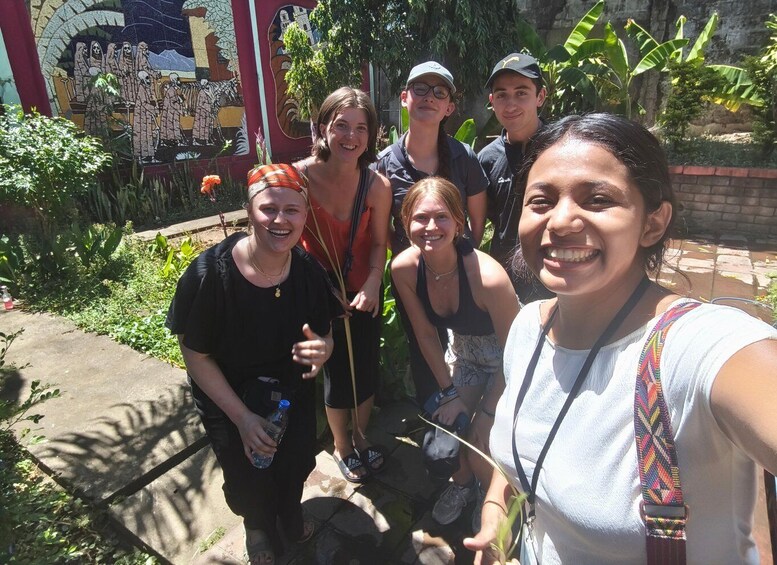 A group of people standing in front of a mosaic mural. 2