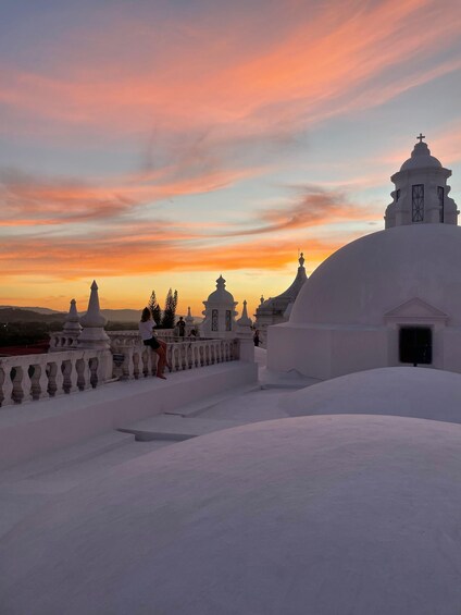 A white-roofed building with a dome and a cross on top, set against a sunset sky. 4