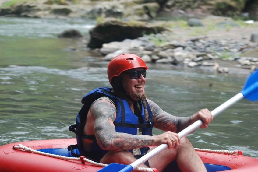 A person in a red raft with a blue life jacket paddling a river. 3