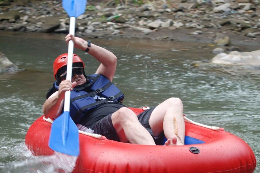 A person in a red inflatable raft paddling a blue paddle. 4