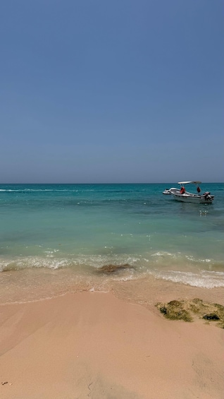 A beach with clear turquoise water, a boat with a canopy, and a lifebuoy. 3