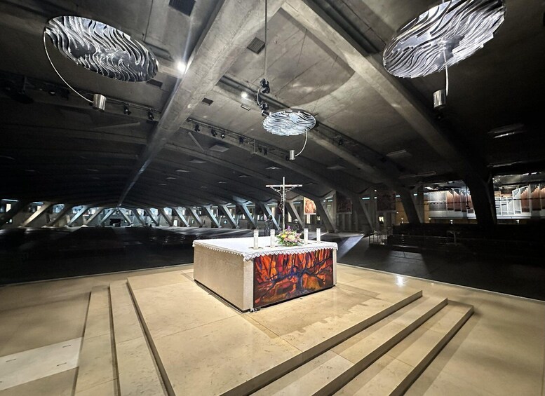 An interior space with a central altar, hanging light fixtures, and a tiled floor. 5