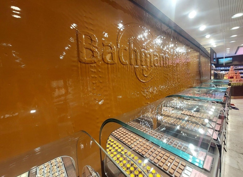 A bakery with a shiny brown wall and glass display cases filled with pastries. 2