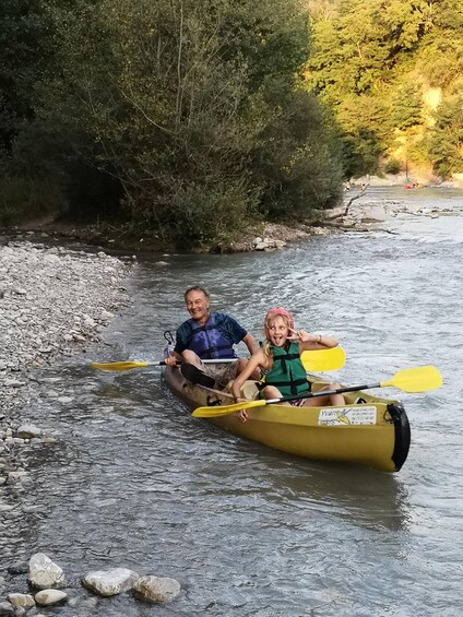Two people in a yellow canoe on a river surrounded by rocks and trees. 2