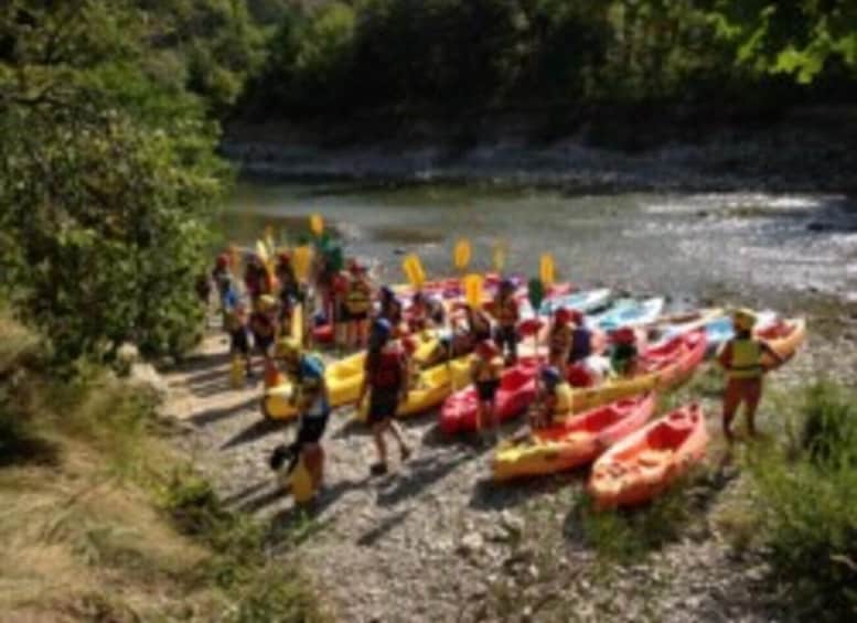 People standing beside colorful kayaks by a river. 3