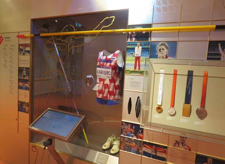 A sports exhibit with medals, a volleyball net, and a display of athletic shoes. 5