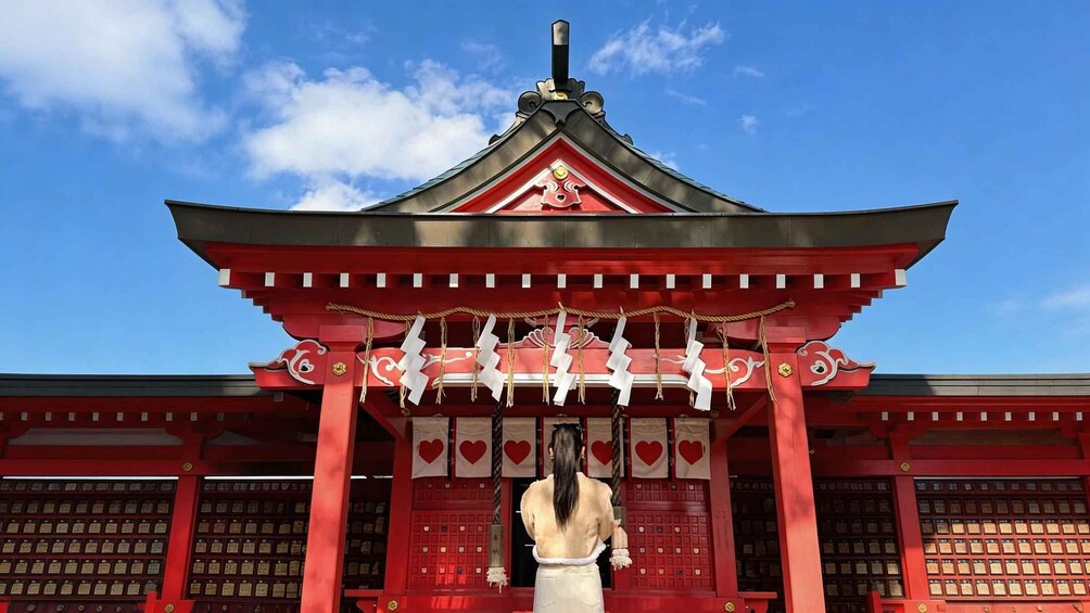 A traditional red and black pagoda with a person standing in front. 2